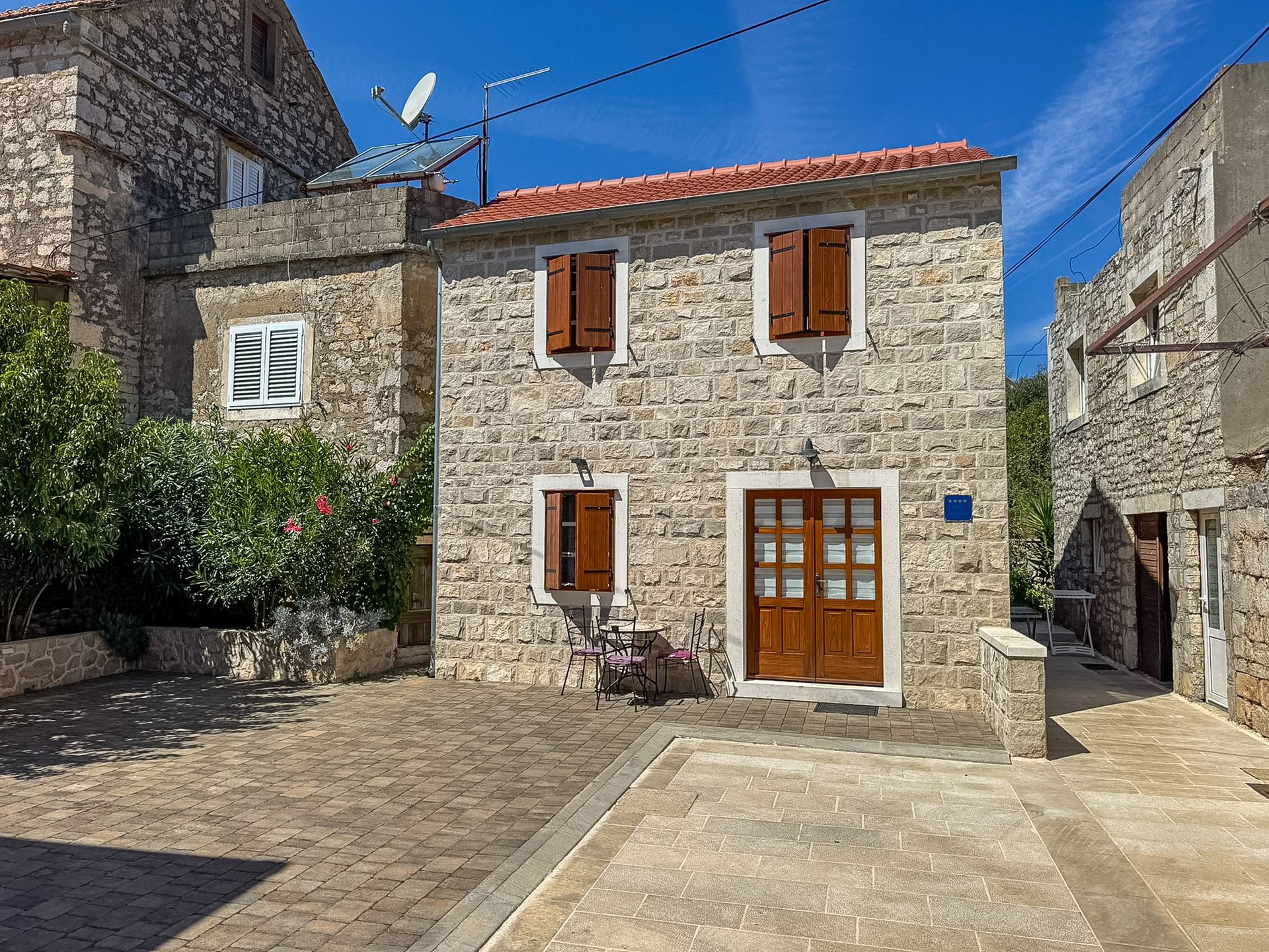 House Tia stone entrance with potted plants and wooden shutters