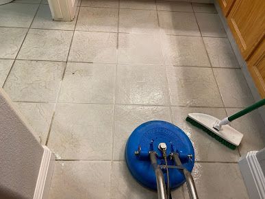 A tile floor is being cleaned with a mop and brush.