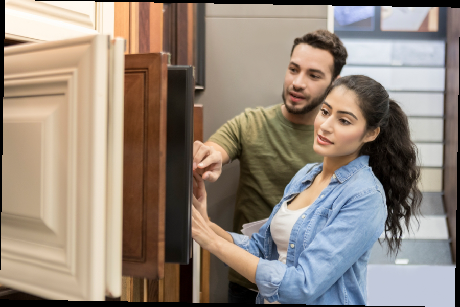 Two people examining wooden cabinet finishes in a showroom