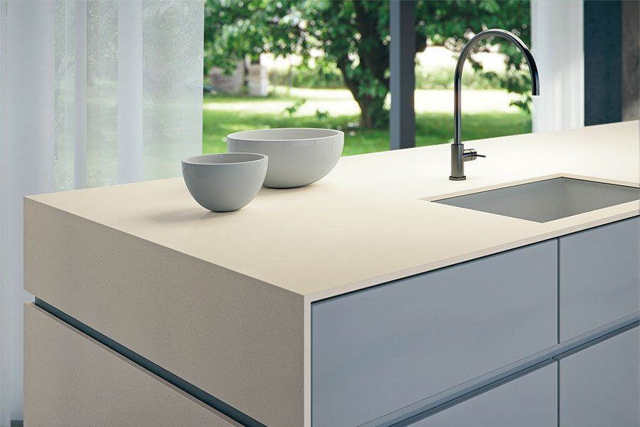Modern kitchen island with two bowls, sink, and faucet by a bright window