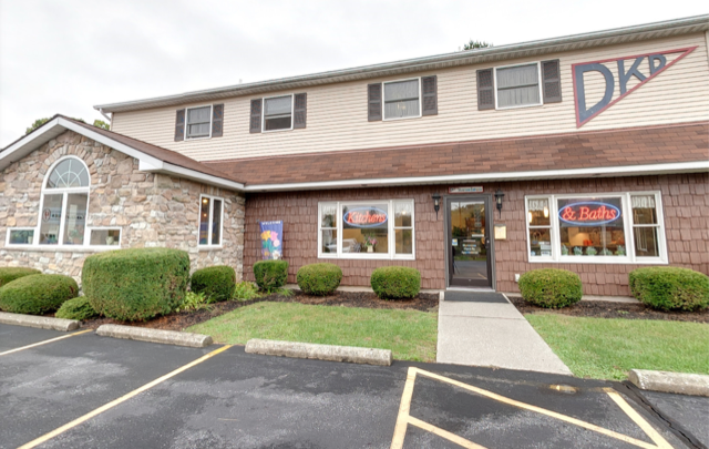 Brick office building with parking lot, sidewalk, and DKP sign above the entrance