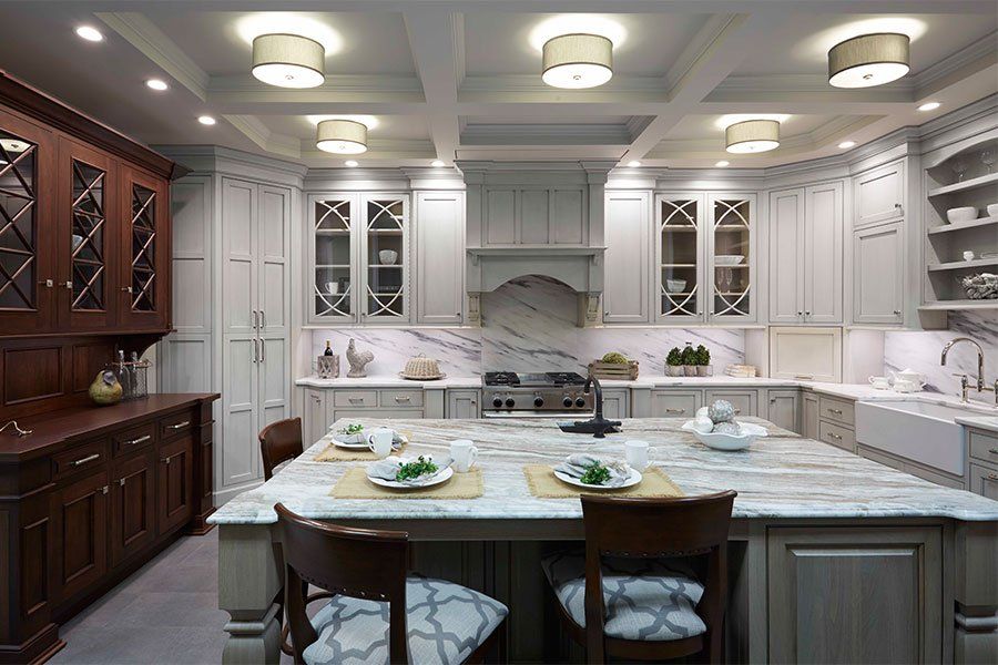 Elegant white kitchen with marble island, dark wood cabinets, and recessed ceiling lights.