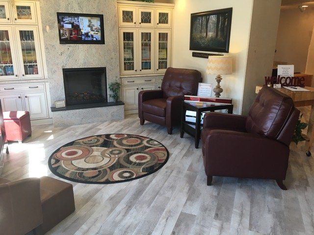 Cozy living room with fireplace, TV, leather chairs, white cabinets, and round patterned rug.