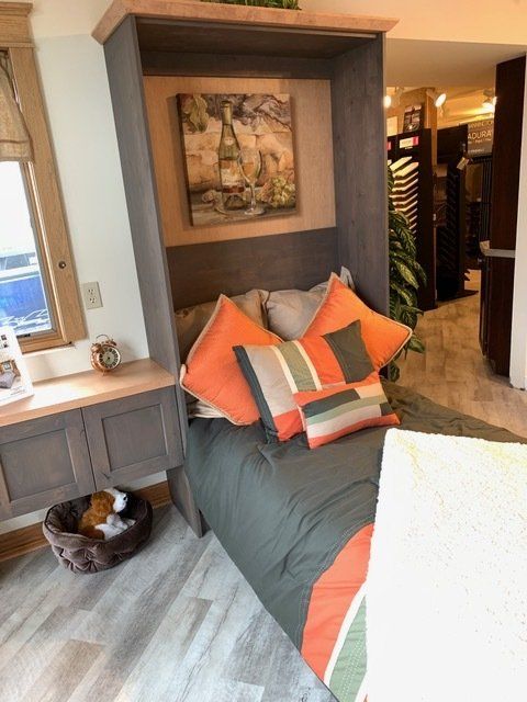 Cozy bedroom nook with a gray daybed, orange pillows, wall art, and built-in storage.