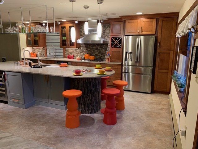 Modern kitchen with island, stainless steel fridge, orange stools, and pendant lights