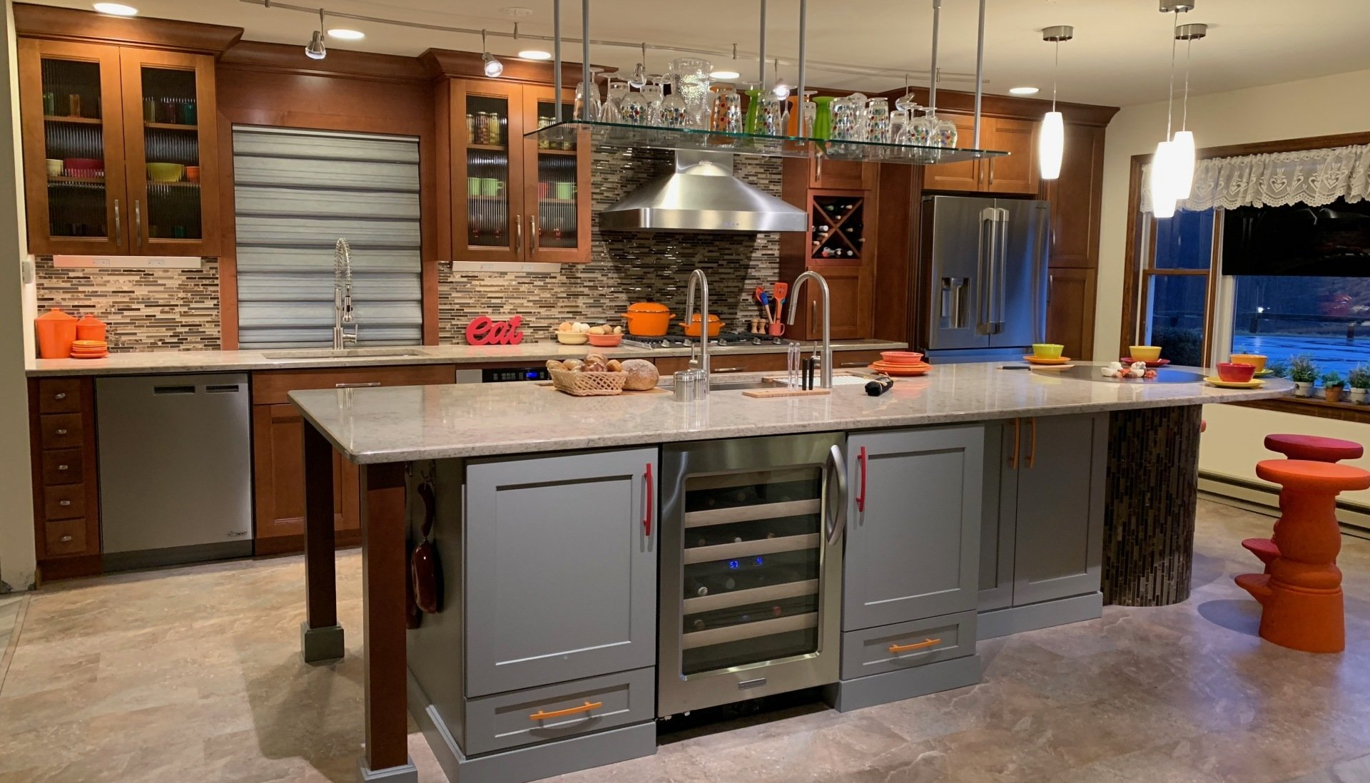 Modern kitchen with a large island, stainless appliances, wood cabinets, and warm pendant lighting