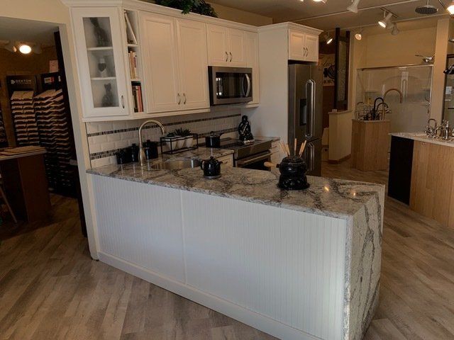 Bright kitchen with white cabinets, granite island, and stainless-steel appliances in an open floor plan.