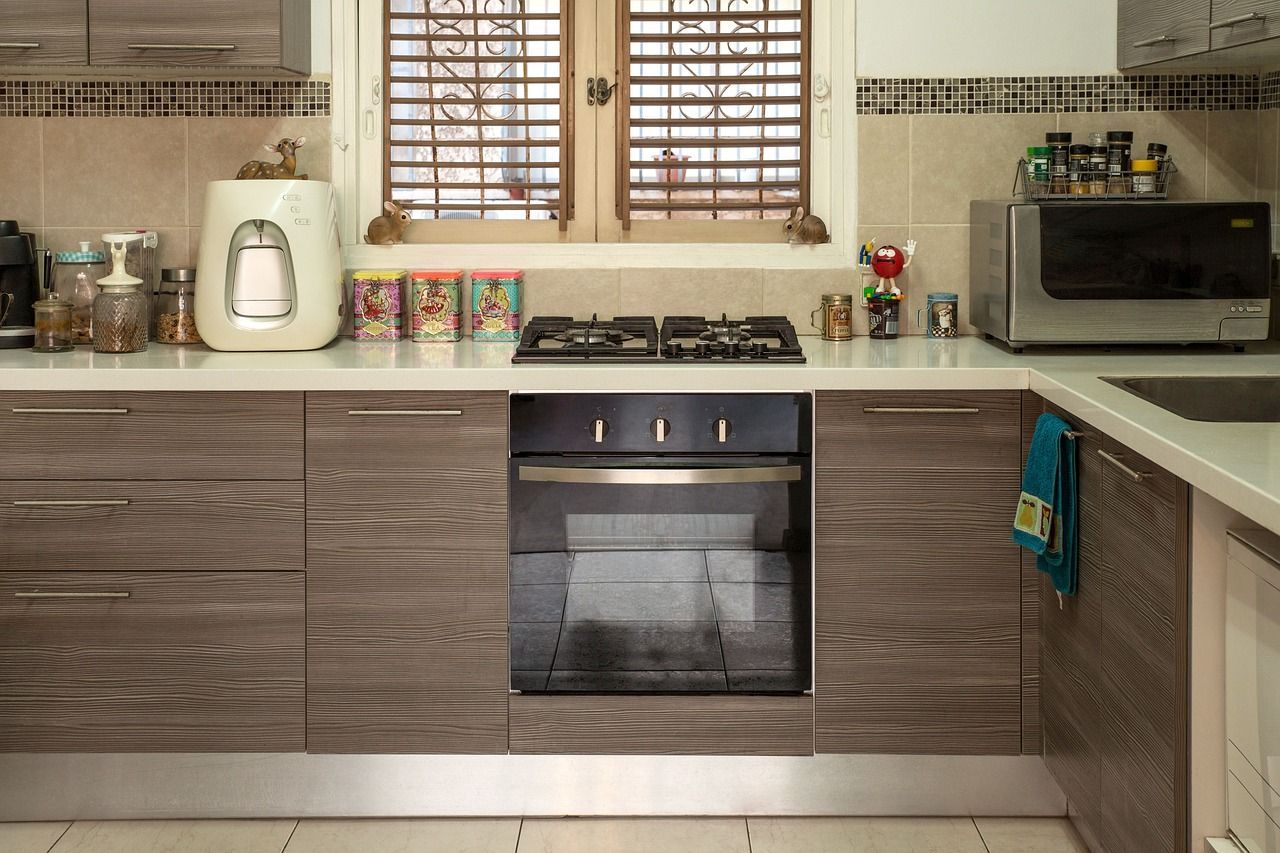 Modern kitchen with wood cabinets, countertop appliances, oven, and window blinds.