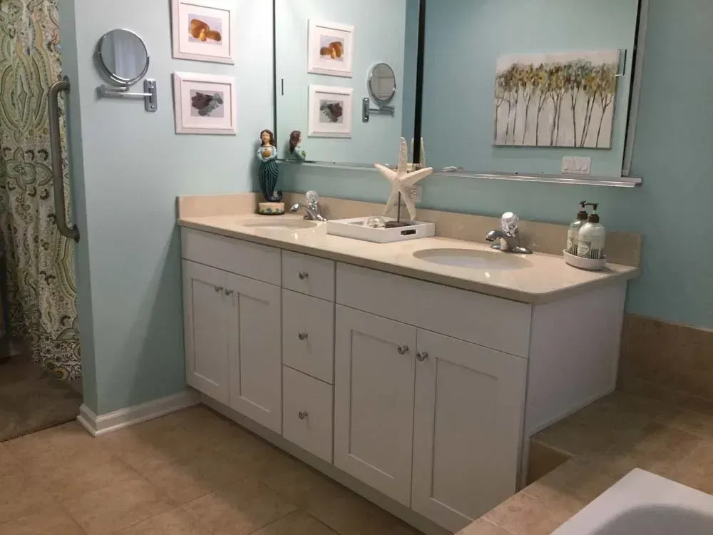 Light blue bathroom with double vanity, mirror, wall art, and shower curtain.