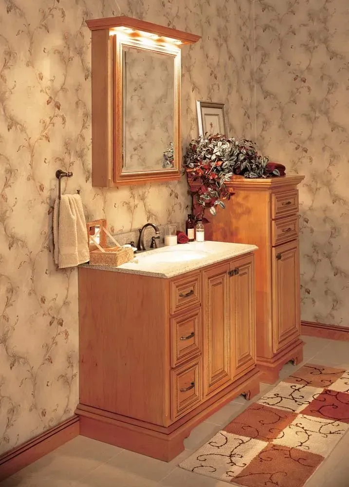 Wooden bathroom vanity with lit mirror, floral wallpaper, and patterned tile floor