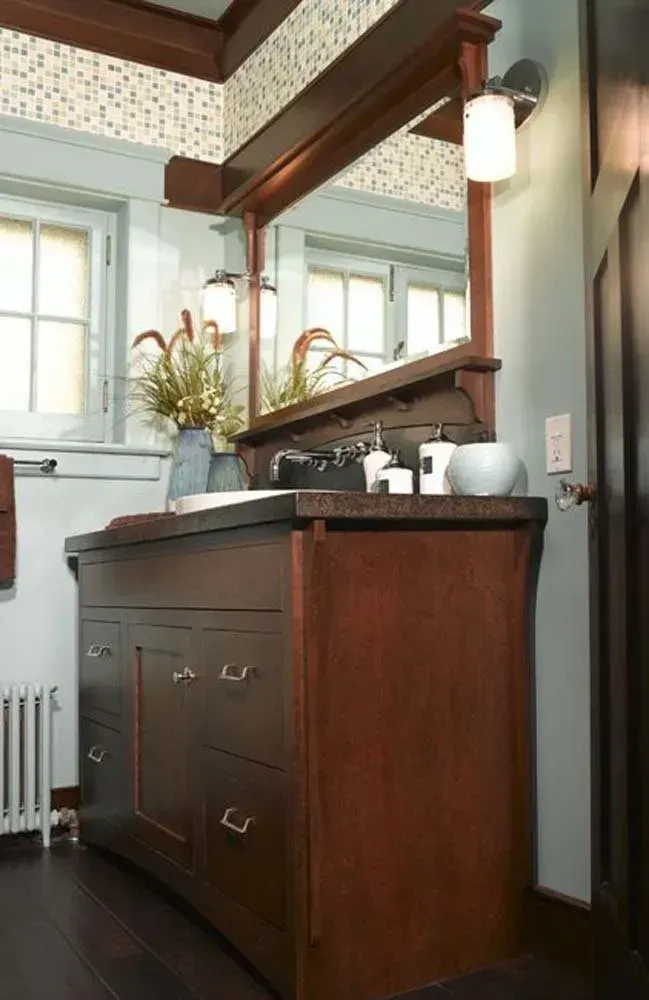Bathroom vanity with wood cabinets, mirror, sink, and hanging light in a bright room