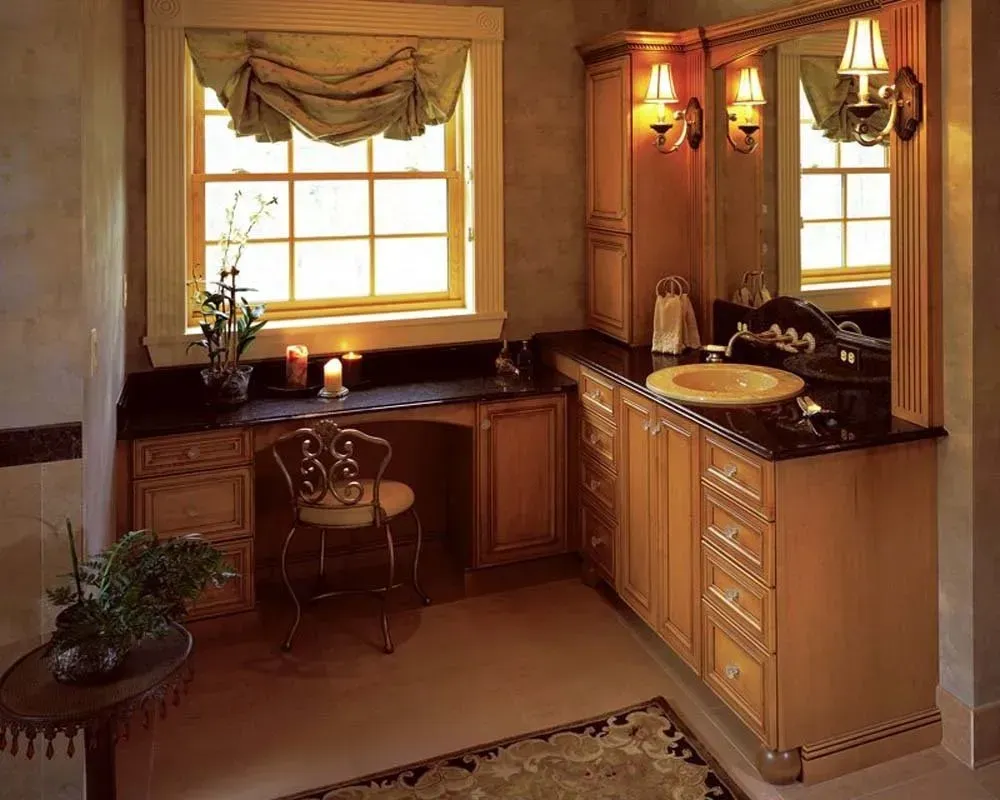 Warm kitchen nook with wood cabinets, window, sink, and warm lighting