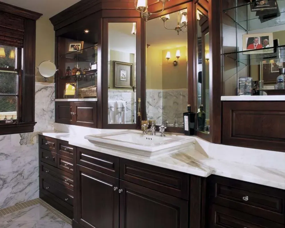 Elegant bathroom vanity with dark wood cabinets, marble countertop, and ornate mirror trim