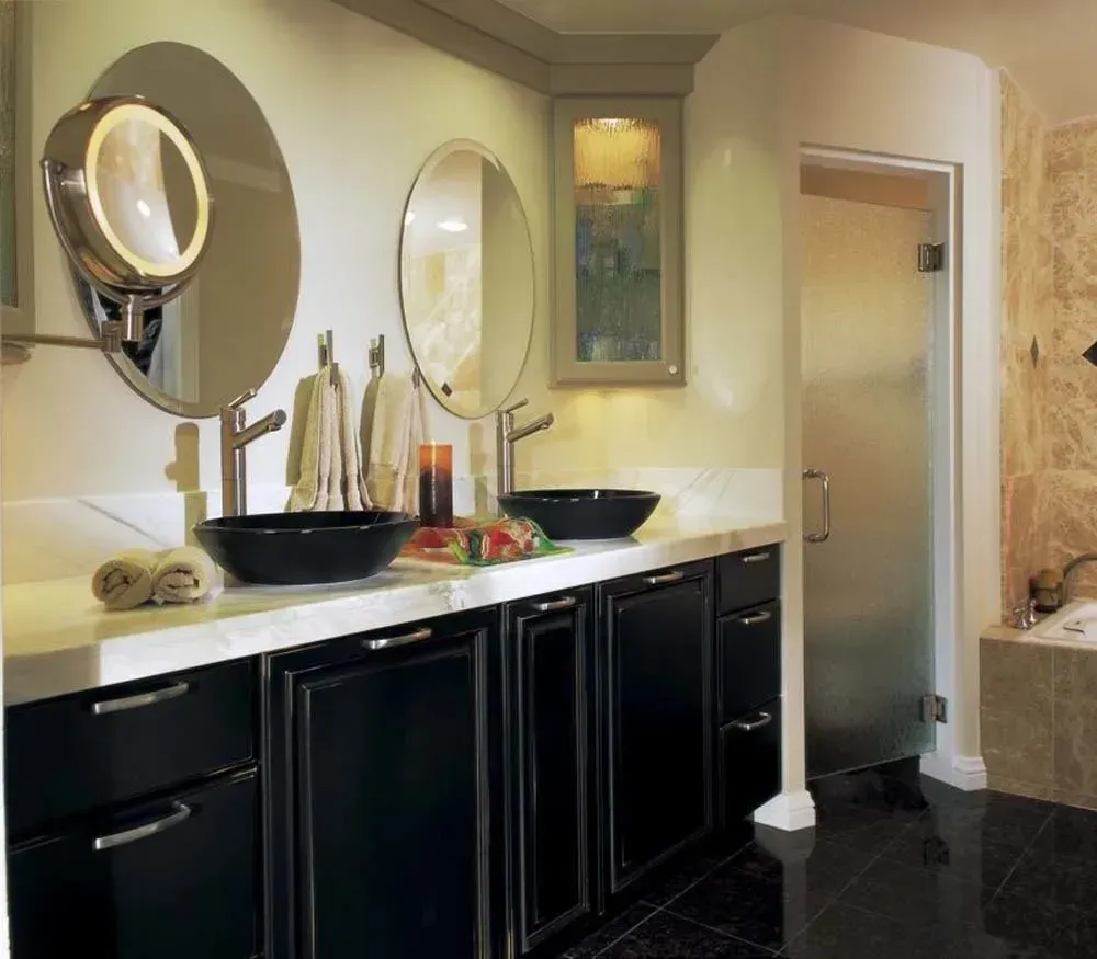 Modern bathroom with black vanity, white countertop, mirrors, and glass shower door