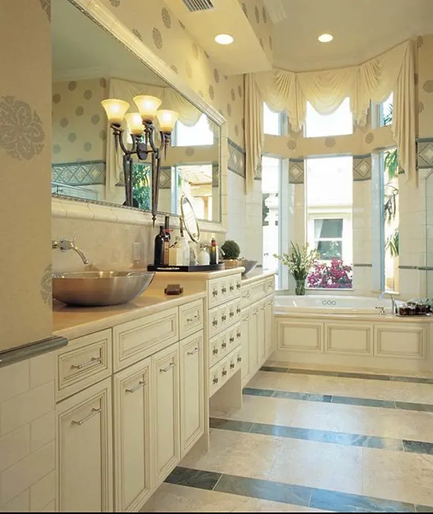 Elegant cream-colored kitchen with large bay windows, dark countertops, and blue-striped tile floor
