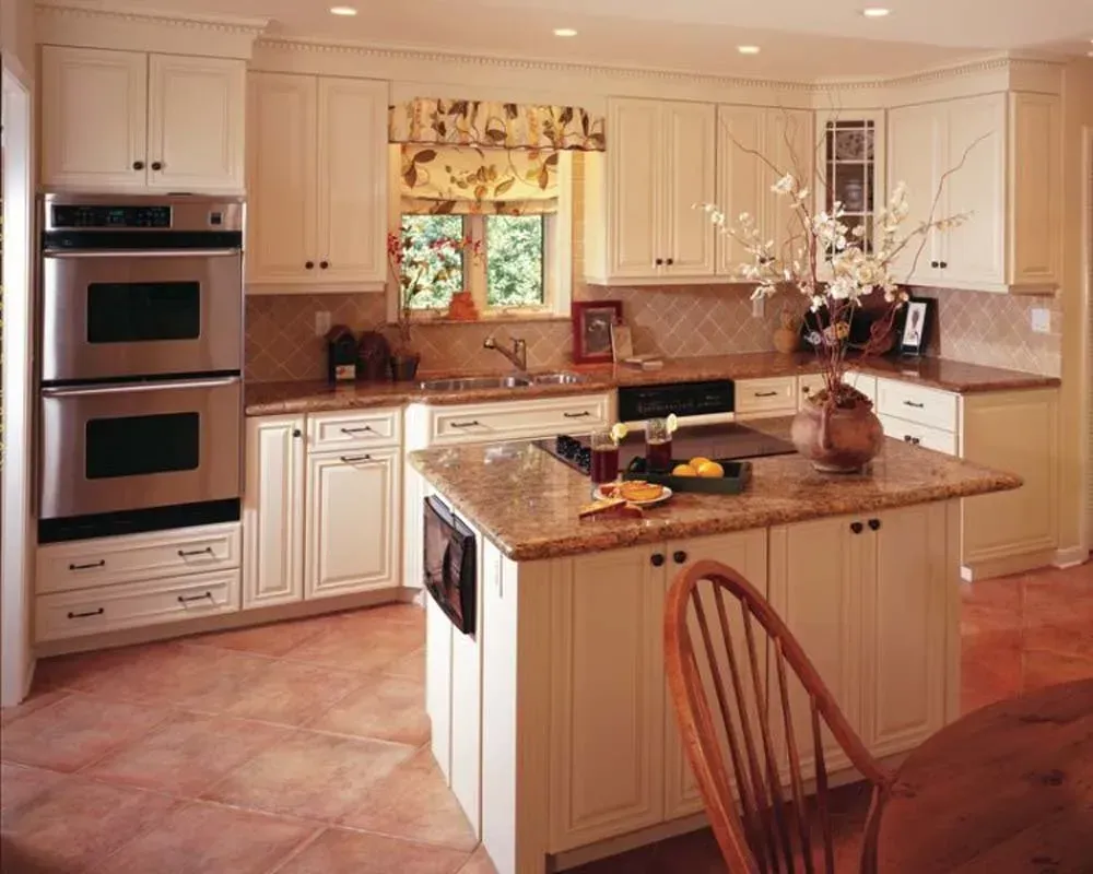 Bright cream kitchen with island, built-in ovens, tiled floor, and window over the sink