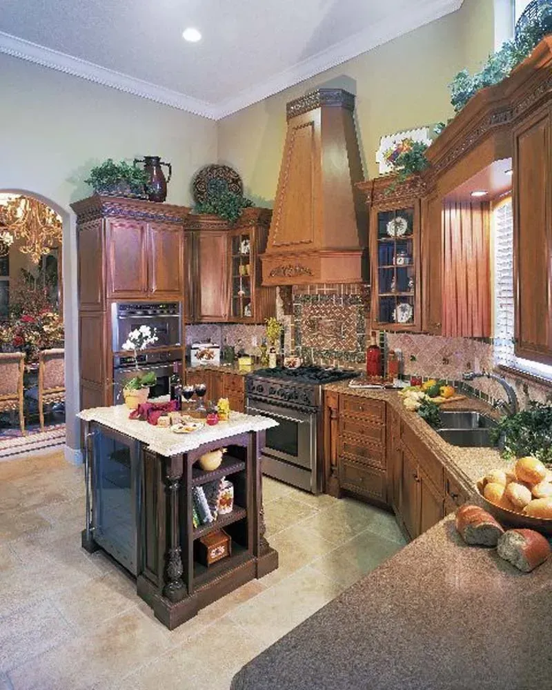 Warm kitchen with wood cabinets, stone island, and a copper range hood, bright with natural light.
