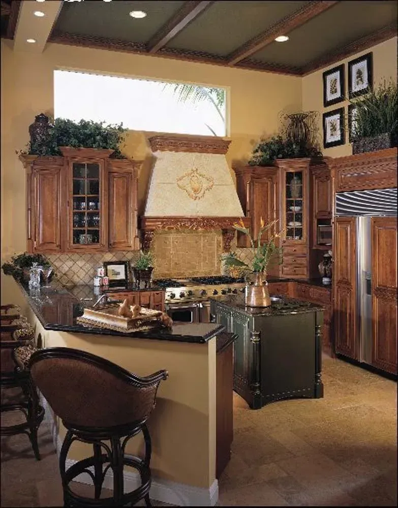 Elegant kitchen with wood cabinets, granite island, and stainless steel refrigerator, warmly lit.