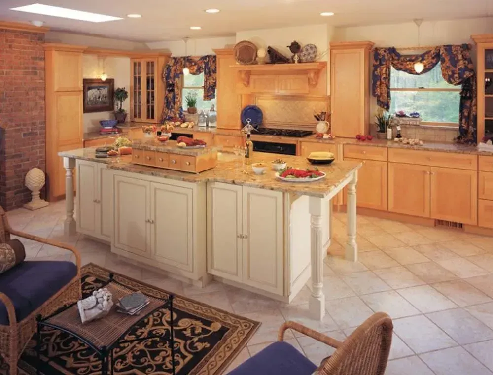 Spacious beige kitchen with central island, wood cabinets, tiled floor, and floral window curtains