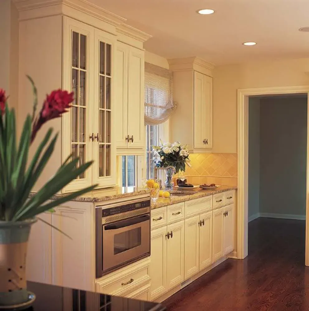 Bright kitchen with white cabinets, stainless oven, hardwood floor, and flowers on the counter.