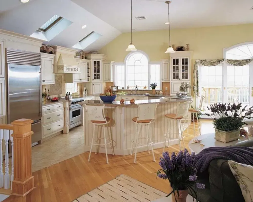 Bright, airy kitchen with island, bar stools, white cabinets, skylights, and hardwood floors