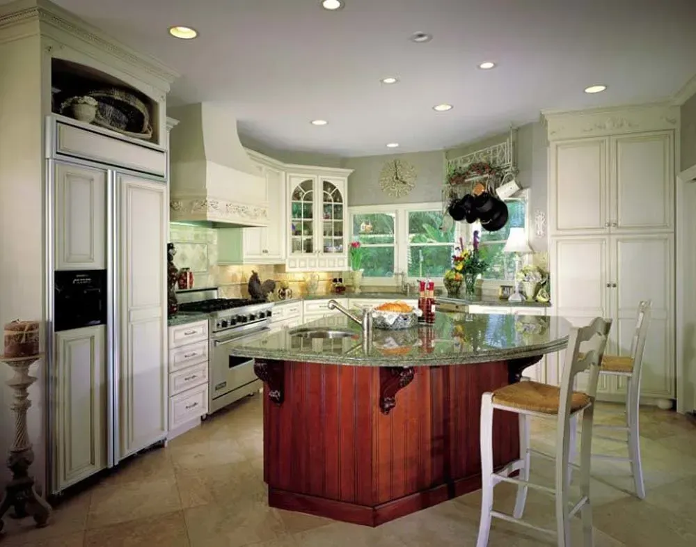 Bright kitchen with white cabinets, central island, granite counters, and a window seat by large windows.