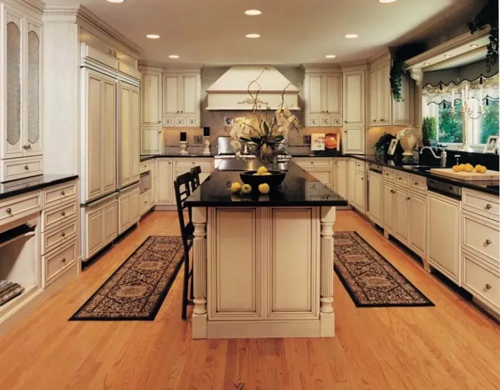 Bright, spacious cream kitchen with a large black island, wood floors, and patterned runners