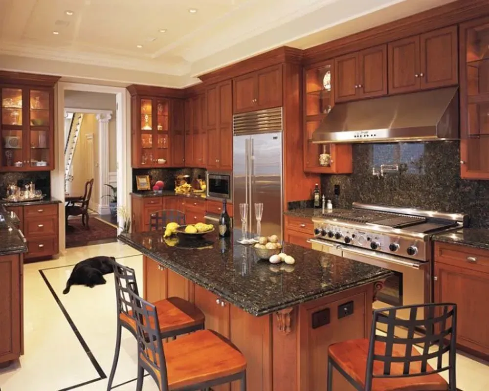 Spacious kitchen with dark wood cabinets, granite island, stainless appliances, and a black cat on the floor.