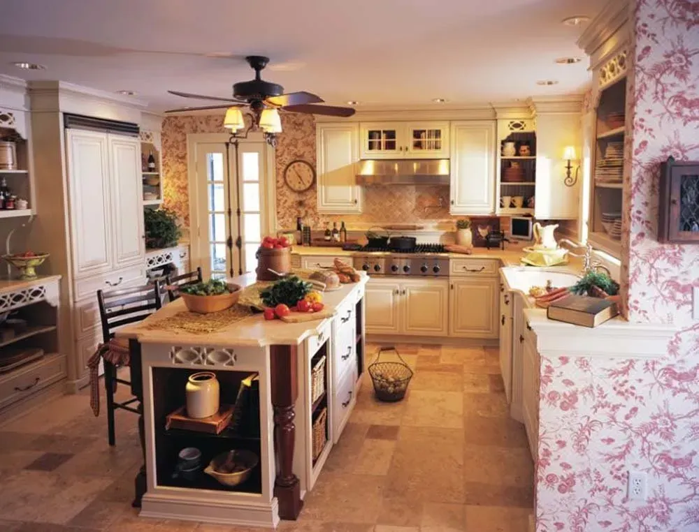 Warm, cozy kitchen with island, white cabinets, floral wallpaper, and hanging lights