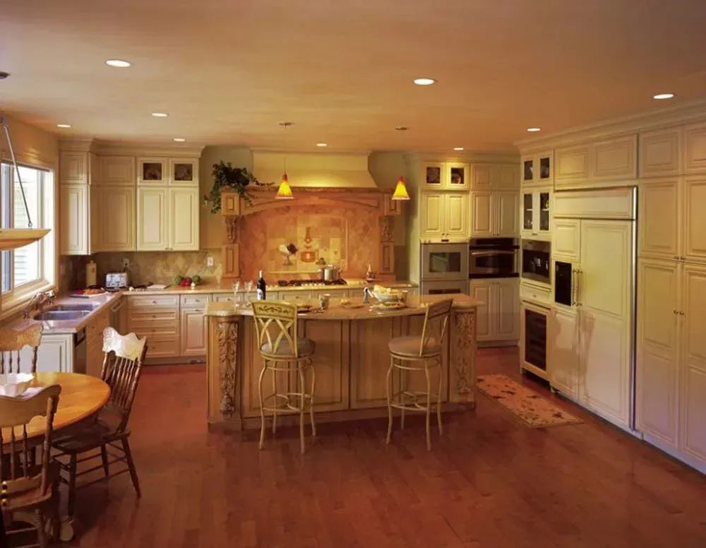Bright modern kitchen with wood floors, central island, white cabinets, and warm pendant lighting
