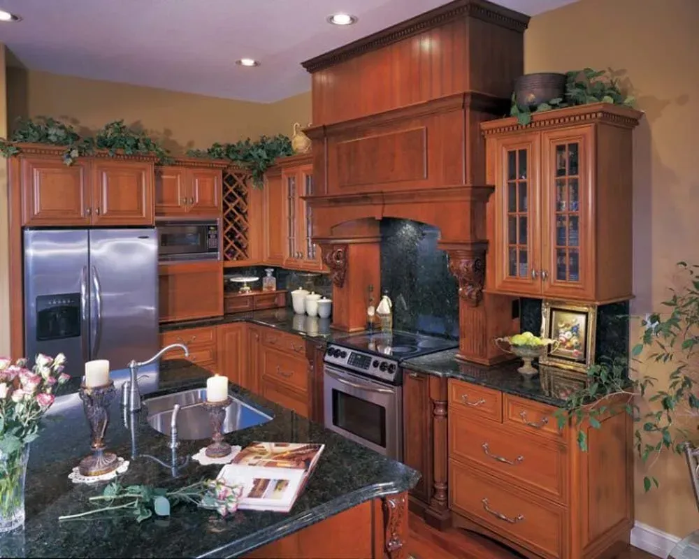 Modern kitchen with dark wood cabinets, stainless steel fridge, black countertops, and central island with flowers.