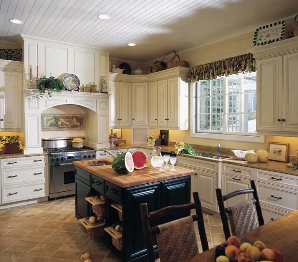 Bright cream kitchen with center island, white cabinets, window over sink, and stainless steel stove