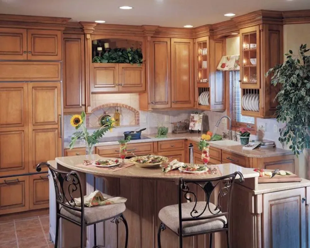 Bright kitchen with wooden cabinets, island seating, and flowers on the counter.
