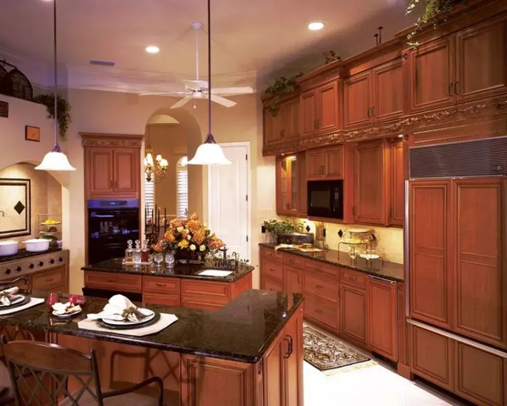 Warm, modern kitchen with dark wood cabinets, island, pendant lights, and stainless steel appliances.