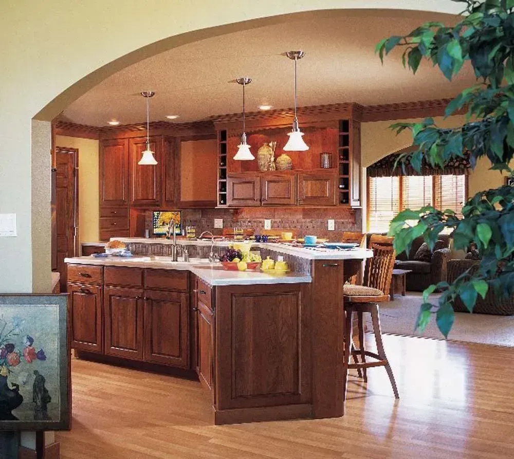 Open kitchen with dark wood cabinets, island, pendant lights, and arched pass-through to dining area