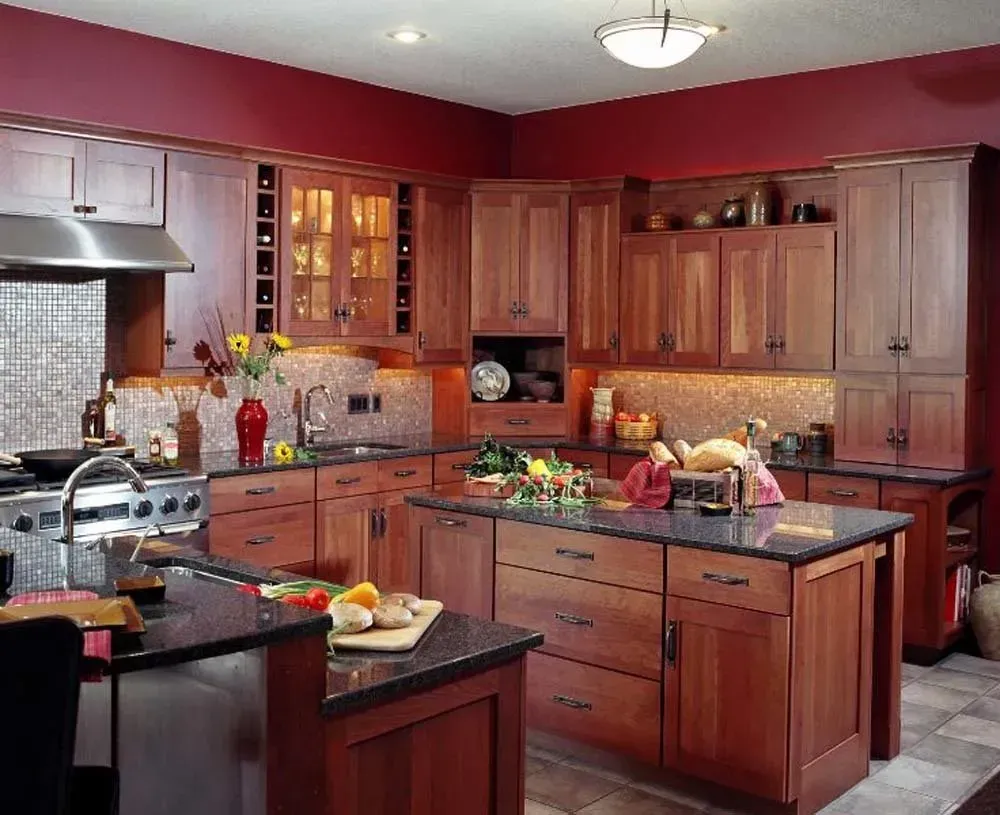 Modern kitchen with wood cabinets, black countertops, island, and warm red walls
