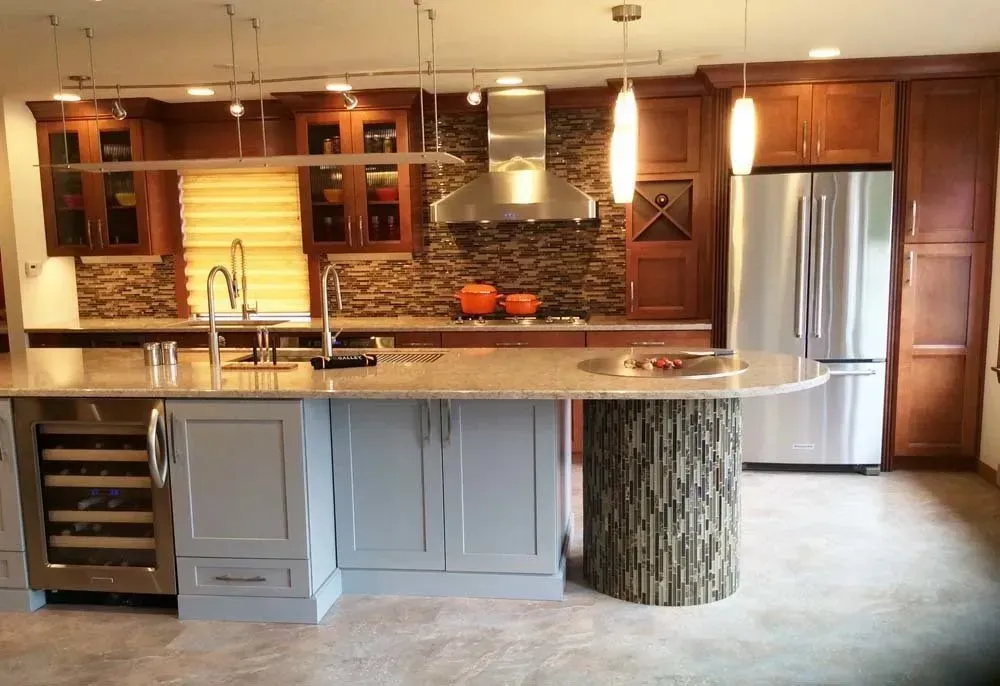 Modern kitchen with wood cabinets, granite island, stainless steel fridge, and warm pendant lighting