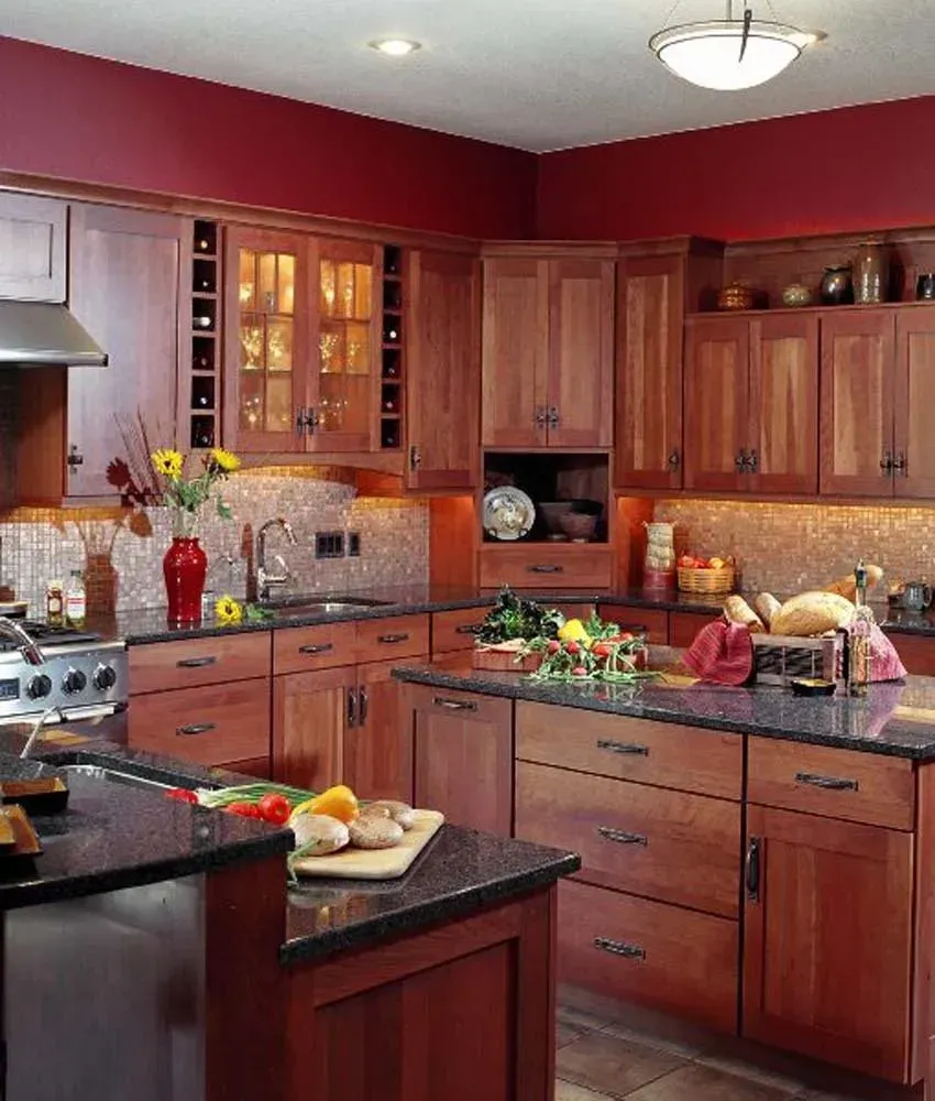 Modern kitchen with cherry cabinets, granite counters, and a central island with fruit and flowers.