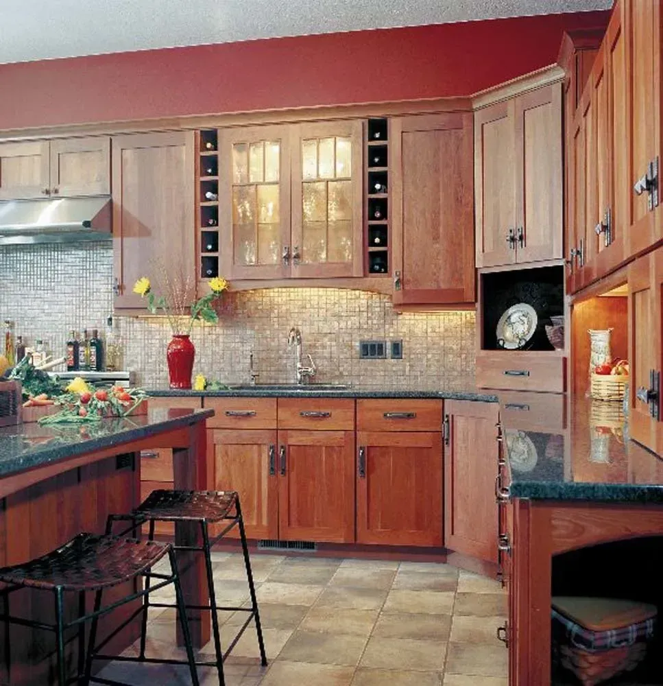 Warm kitchen with wood cabinets, tiled backsplash, granite counters, and a stainless range hood.