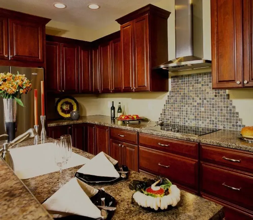 Modern kitchen with cherry cabinets, granite counters, tiled backsplash, and a fruit bowl centerpiece