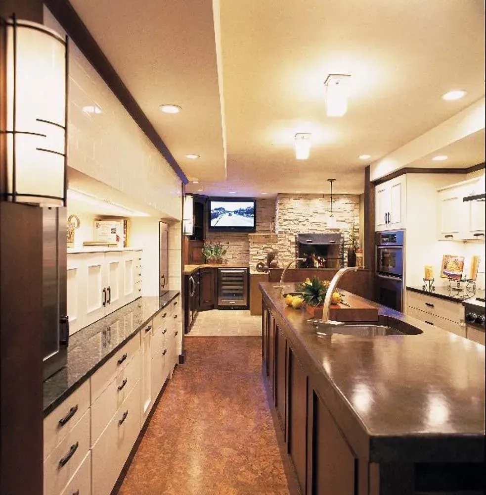 Modern kitchen with a large island, dark countertops, built-in cabinets, and warm recessed lighting
