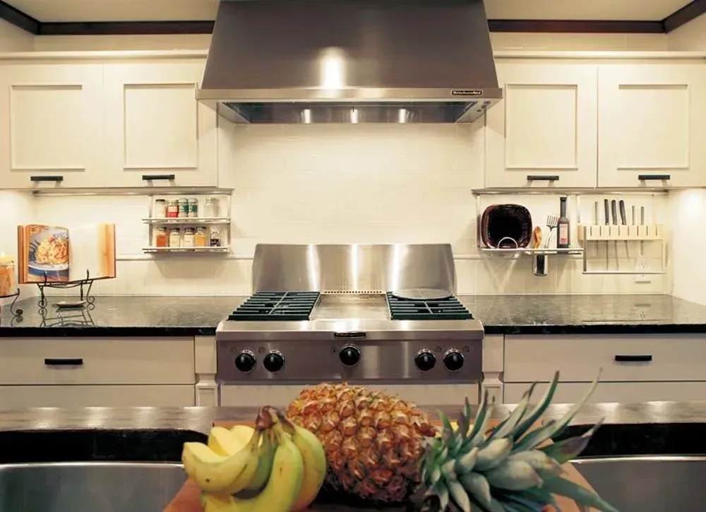 Modern kitchen with stainless steel range, white cabinets, and fruit on the counter.