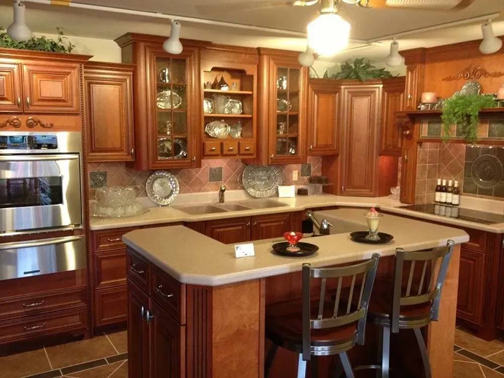 Warm wood kitchen with granite island, stainless oven, glass cabinets, and hanging light fixtures