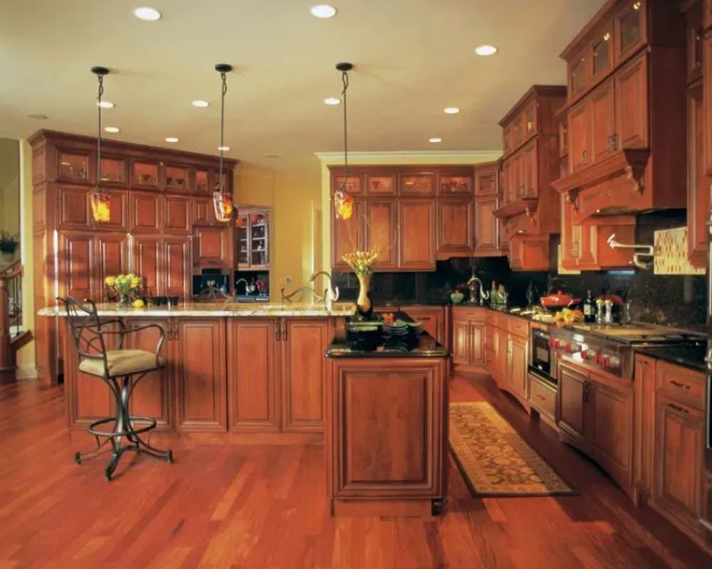 Warm wood kitchen with island, pendant lights, hardwood floors, and stainless steel appliances