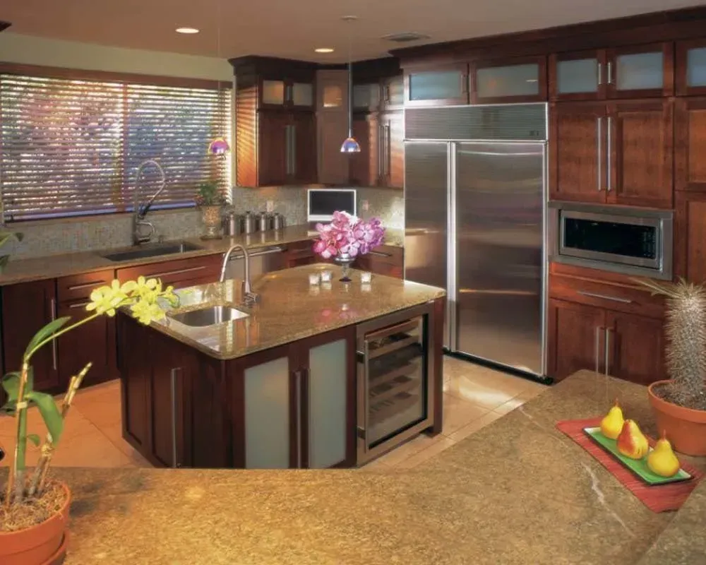 Modern kitchen with stainless steel appliances, dark wood cabinets, and a central island with flowers.