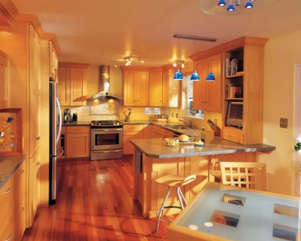 Warm wooden kitchen with stainless steel appliances, island seating, and blue pendant lights