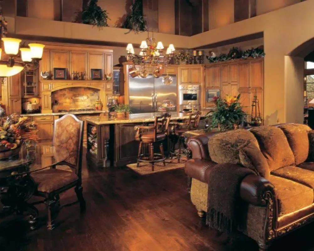 Warm, elegant living room with leather sofa, armchair, fireplace, and chandelier lighting