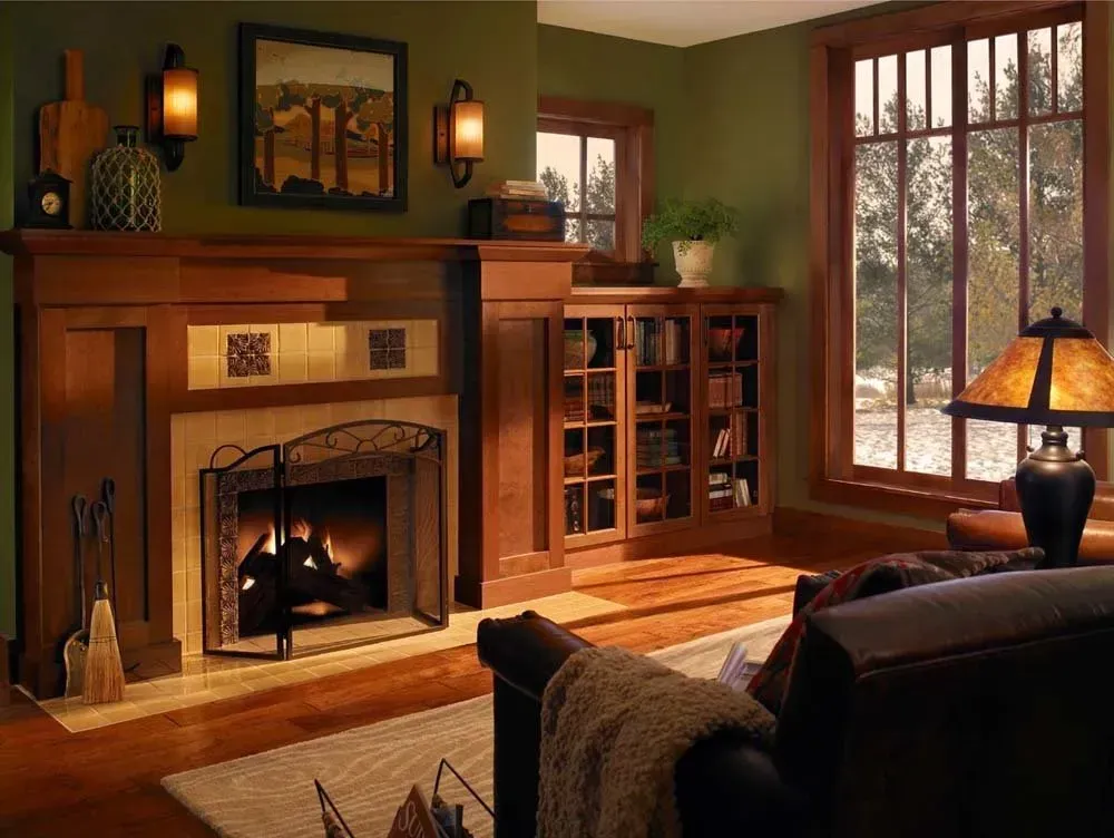 Cozy living room with a lit fireplace, wood furniture, large windows, and a dark sofa by the fire