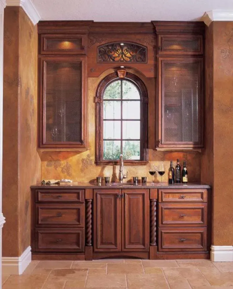 Dark wood kitchen cabinet with arched window and granite countertop in a warm-toned room