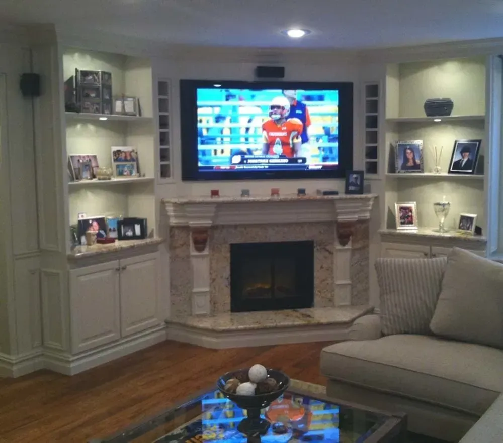 Cozy living room with fireplace, built-in shelves, wall-mounted TV, and beige sofa, warmly lit.